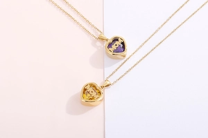 Detail of gold heart MOM necklaces with purple and yellow birthstones for Mother's Day gift