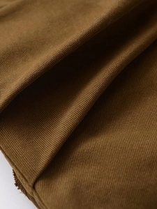 Gros plan détaillé sur la texture du tissu sergé marron caramel et les coutures d'une jupe