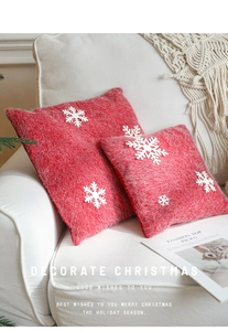 Close-up of red Christmas pillowcases with white snowflake appliques on a sofa