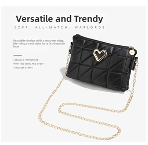 Detail of black quilted shoulder bag featuring gold heart hardware and chain strap