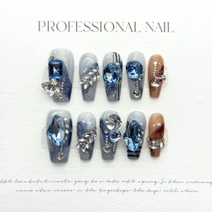 Faux ongles faits main avec effet marbre bleu et ornements de pierres précieuses 3D