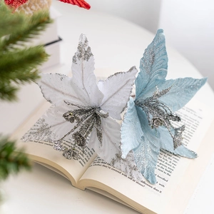 Close-up of white and blue glitter Christmas flowers on a vintage book page decoration