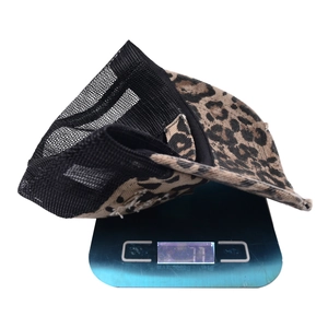 Detailed view of leopard print trucker hat on a digital scale showing 77g weight