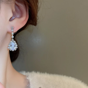 Close-up of silver water drop diamond earrings on model for a luxury look