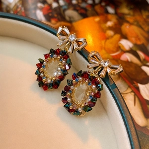 Detail of vintage gold bow earrings with colorful gemstones and pearls on an oil painting background