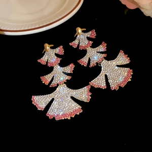 Detail view of gold fan-shaped ginkgo earrings with pink and white rhinestones