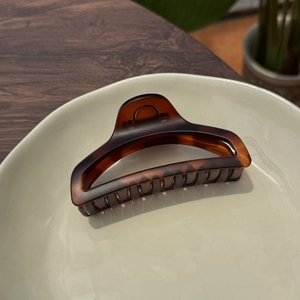 Detail of a 10cm brown tortoiseshell claw clip on a white ceramic plate for long hair