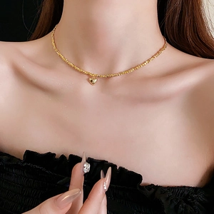 Detail shot of a minimalist gold heart pendant necklace worn on a model's neck