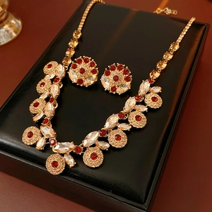 Close-up of vintage gold jewelry set with red and clear zircon in a black leather box