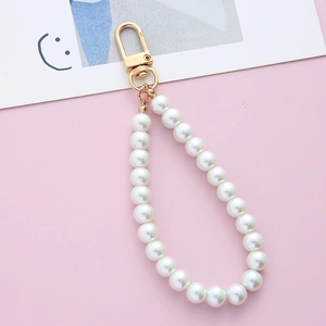 Elegant pearl keychain with white beads and golden lobster clasp on soft pink background