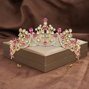 Detailed view of golden baroque crown with pink and white rhinestones on velvet