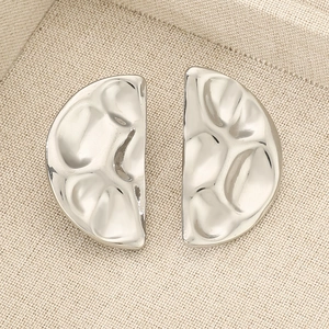 Macro detail of silver hammered D-shape stud earrings on a textured jewelry box