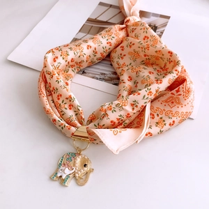 Détail d'un foulard en soie fleurie avec pendentif éléphant doré orné de perles fines
