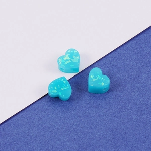 Detailed view of three teal heart-shaped opal resin beads with rainbow glitter and small holes