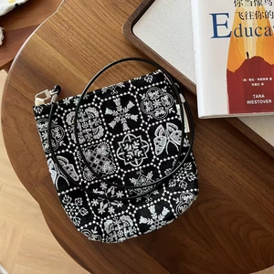 Détail du sac bandoulière vintage en toile noire avec broderies de fleurs et papillons