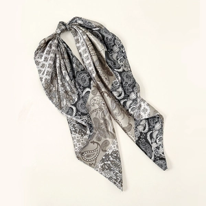 Détail d'un foulard carré en simili soie avec motifs paisley et fleurs en gris.
