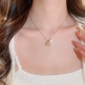 Close-up of gold-plated pony and coin pendant necklace worn on a model's neck