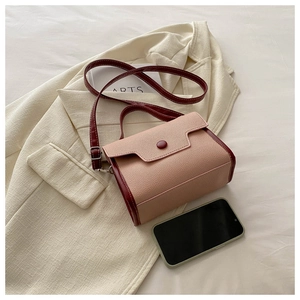 Detail of pink and dark red patchwork crossbody bag with lychee texture and round buckle