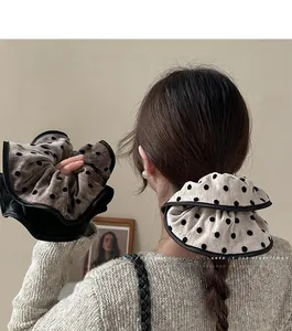 Detail of oversized polka dot scrunchies with black piping shown on a model's hair
