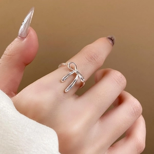 Close-up of a silver bow-shaped open ring on a finger with smooth polished finish