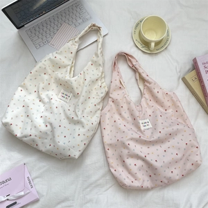 Detailed view of floral canvas tote bags in cream and pink on a cozy white bed setting
