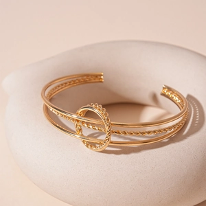 Macro detail of golden triple-layered geometric cuff with twisted rope ring detail