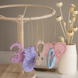 Group of cat-themed resin pendants in pastel colors hanging on a wooden display stand