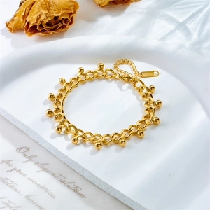 Elegant gold stainless steel chain bracelet featuring small ball pendants on a minimalist tray