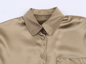 Détail d'une chemise en soie champagne montrant le col à revers et les boutons