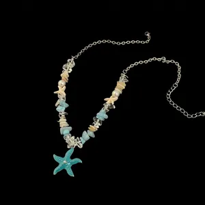 Détail du collier avec pendentif étoile de mer bleue, éclats d'aigue-marine et coquillages