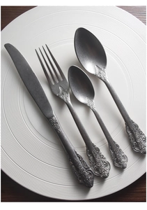 Detailed view of vintage embossed 304 stainless steel cutlery set on a ceramic plate
