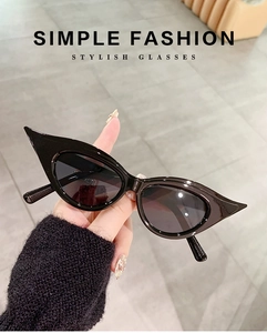 Detailed view of hand-held black cat-eye sunglasses with sharp pointed edges and dark lenses
