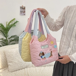 Bolsos tote acolchados en rosa, amarillo y azul sostenidos por modelo en una sala
