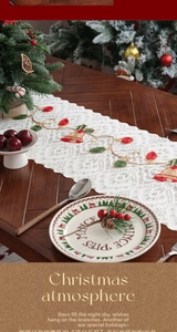 Close-up of festive Christmas lace table runner with red bell embroidery and golden thread