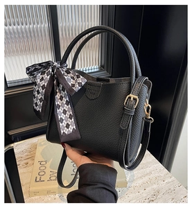 Detailed view of black litchi pattern bucket bag with decorative checkered silk scarf