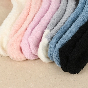 Nahaufnahme weicher Plüschsocken aus Korallenvlies in verschiedenen Farben auf Stoff