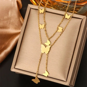 Detail of double-layer gold butterfly pendant necklace on a champagne jewelry stand
