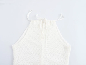 Detail of white halter neck dress featuring textured geometric knit fabric and tie design