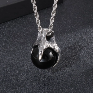 Macro shot of silver eagle claw pendant with a black round bead on a twisted chain