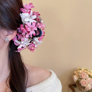 Détail d'une pince à cheveux avec fleurs en tissu rose portée par un mannequin sous lumière