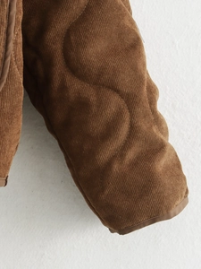 Detailopname van bruine gewatteerde corduroy textuur en de mouw van het damesjack