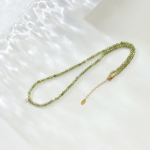 Close-up of olive green zircon beaded necklace with gold lobster clasp and extension chain