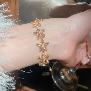 Detailed close-up of zircon flower bracelet with golden base and champagne stones on wrist