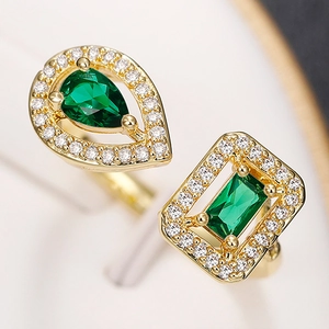 Macro shot of gold open ring with green water-drop and rectangle zircon stones