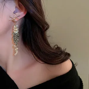 Orecchini a fiore con cristalli e nappe con perline verdi indossati dalla modella