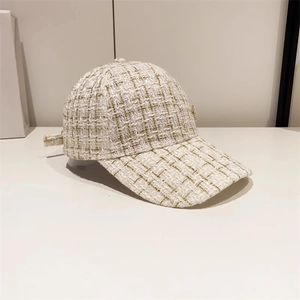 Detail of cream bouclé baseball cap featuring gold metallic threading and texture