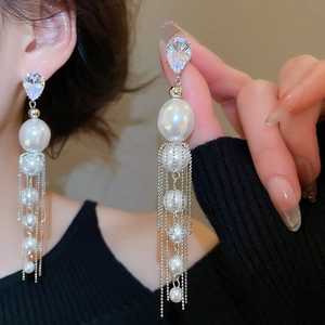 Détail de boucles d'oreilles à pampilles en perles avec clous en zircon sur l'oreille