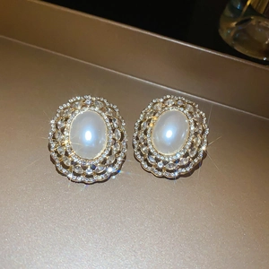 Macro view of French vintage pearl earrings with gold hollow diamond inlay detail