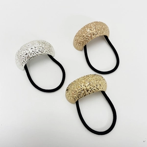 Detail of three elastic hair ties with hammered gold and silver textured metal U-shaped accents