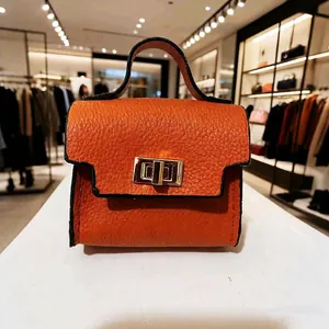 Detail of orange lychee leather mini bag keychain with golden twist lock and top handle